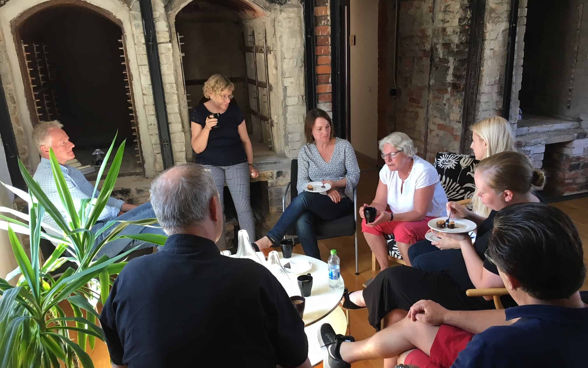 Bilden visar en grupp människor som sitter runt ett bord och samtalar