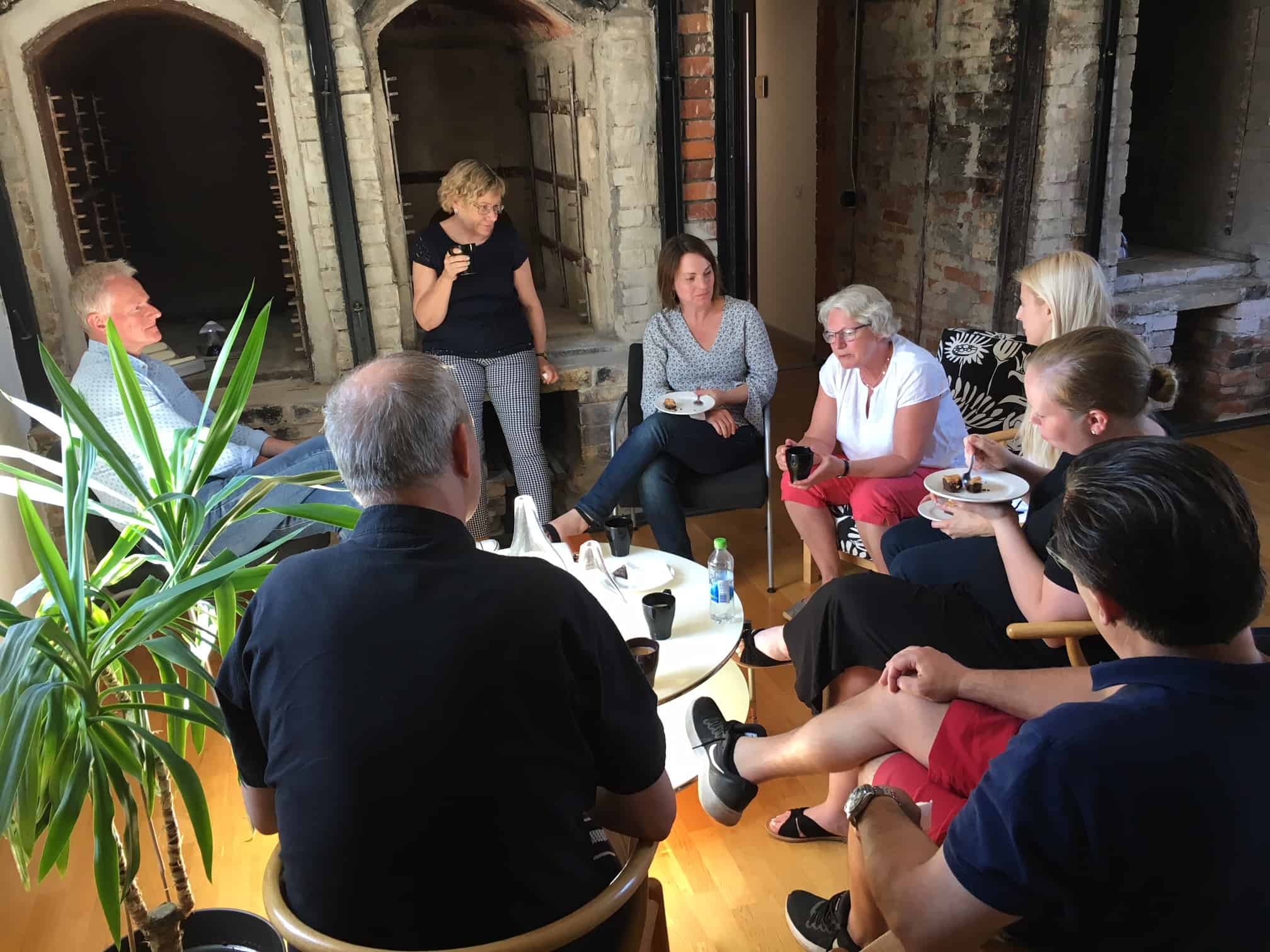 Bilden visar en grupp människor som sitter runt ett bord och samtalar