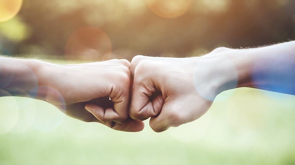 bilden visar en fistbump: två knutna händer som möts